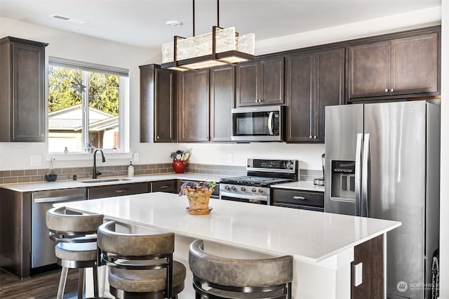 kitchen with sink, hanging light fixtures, a center island, and appliances with stainless steel finishes