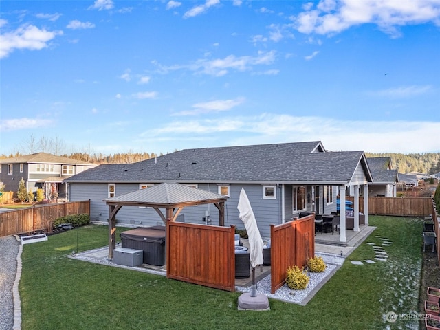 rear view of house featuring a yard, a gazebo, an outdoor hangout area, and a hot tub