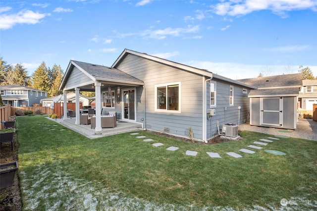 back of house featuring a yard, central AC, a patio, a storage unit, and an outdoor hangout area