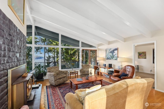 living room featuring lofted ceiling with beams, hardwood / wood-style floors, and a fireplace