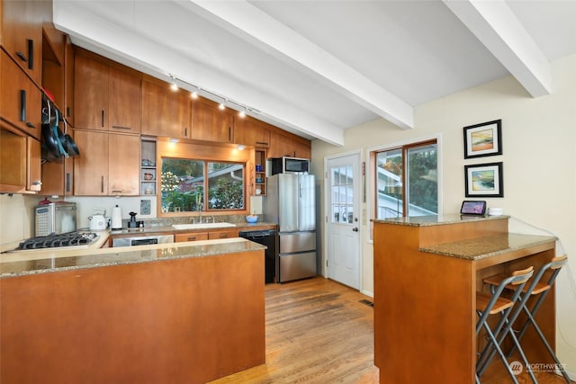 kitchen featuring stainless steel appliances, light stone countertops, a wealth of natural light, and kitchen peninsula