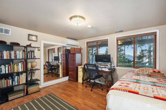 bedroom featuring hardwood / wood-style floors and a wall mounted air conditioner