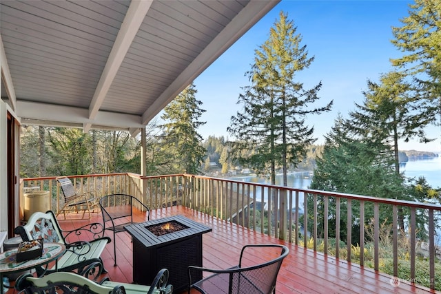 wooden terrace with a water view and a fire pit