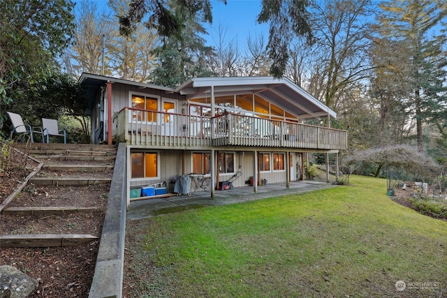 back of property featuring a wooden deck, a lawn, and a patio area