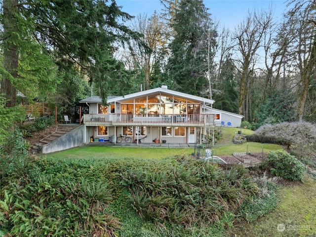 rear view of house with a wooden deck and a lawn