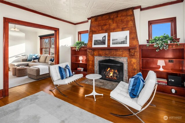 living room featuring hardwood / wood-style flooring, ornamental molding, and a fireplace