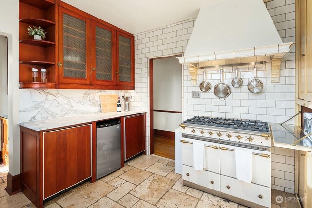 kitchen featuring premium range hood, decorative backsplash, dishwasher, and range with two ovens