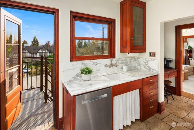 kitchen featuring tasteful backsplash, dishwasher, light stone countertops, and sink