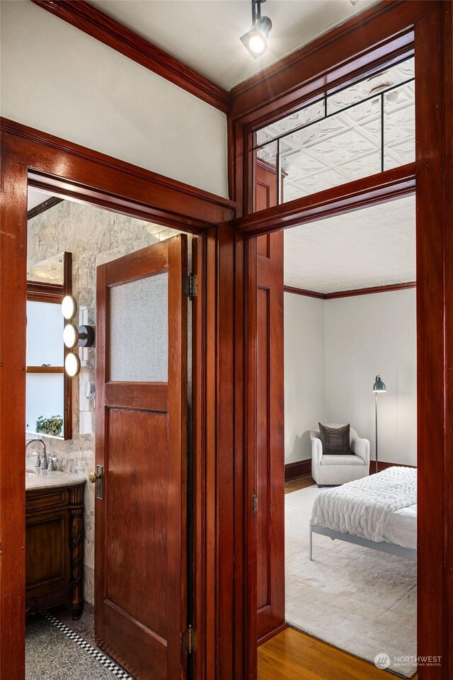 bathroom featuring crown molding, wood-type flooring, and vanity