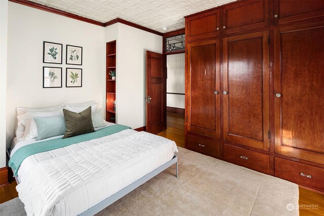 bedroom with ornamental molding, a closet, and light wood-type flooring