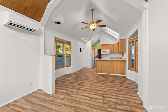 interior space with vaulted ceiling, ceiling fan, light hardwood / wood-style floors, and an AC wall unit