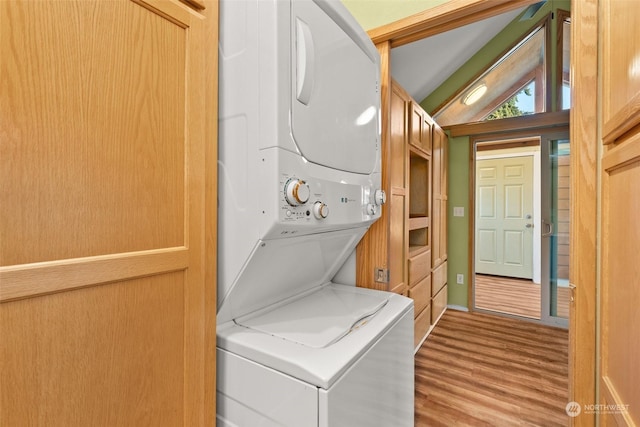 laundry room featuring stacked washer / dryer and light hardwood / wood-style floors