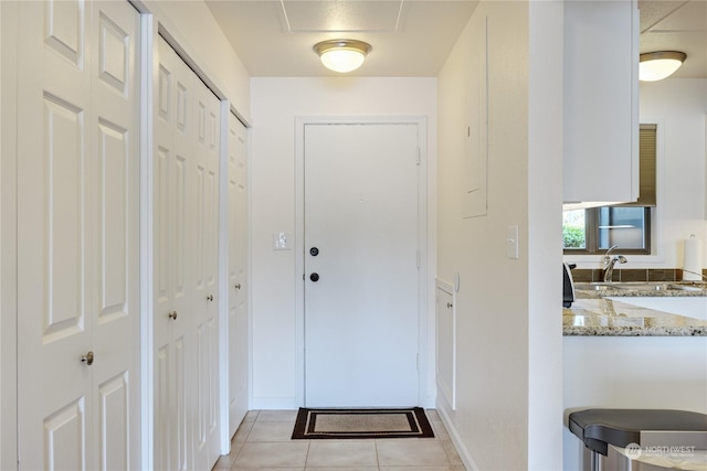 doorway to outside featuring light tile patterned flooring and a sink