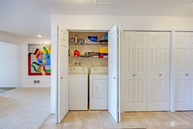 clothes washing area with laundry area, light tile patterned floors, visible vents, light colored carpet, and washing machine and dryer