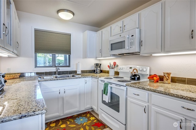 kitchen featuring white appliances, a sink, light stone counters, and white cabinets