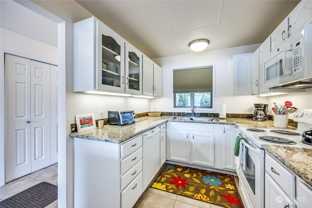 kitchen with glass insert cabinets, white cabinetry, a sink, light stone countertops, and white appliances