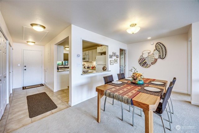 dining room with light carpet, light tile patterned floors, and baseboards