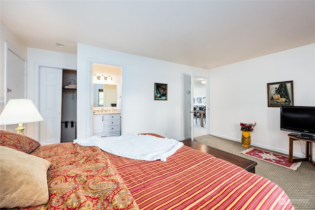 carpeted bedroom featuring ensuite bathroom and baseboards