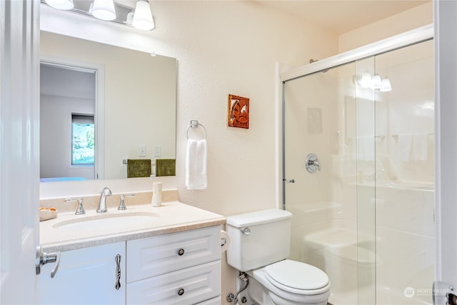 bathroom featuring toilet, a shower stall, and vanity