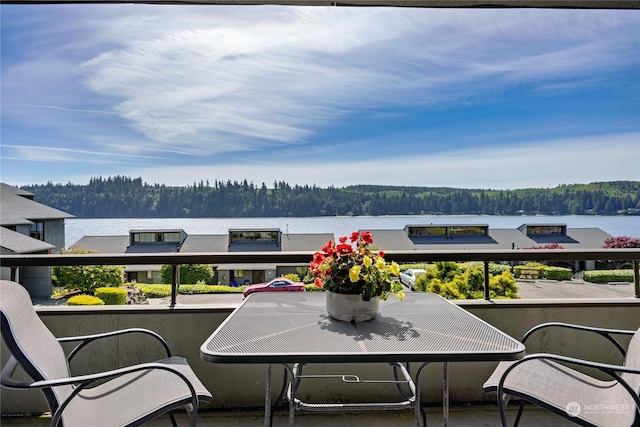 balcony featuring a water view and a wooded view