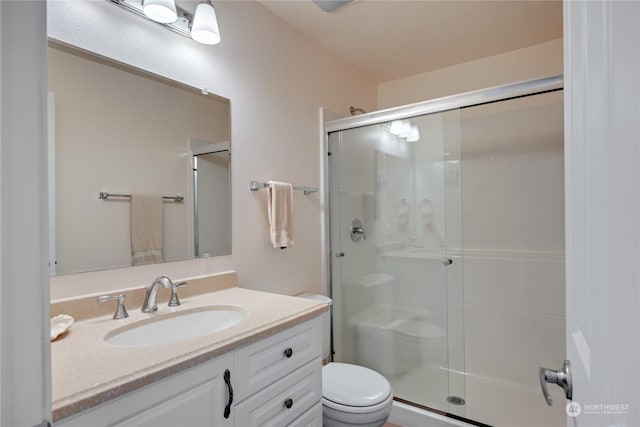 bathroom featuring toilet, a shower stall, and vanity