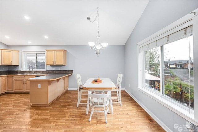 kitchen featuring pendant lighting, a kitchen breakfast bar, light brown cabinetry, and light hardwood / wood-style flooring