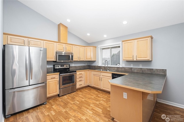 kitchen with lofted ceiling, sink, kitchen peninsula, stainless steel appliances, and light hardwood / wood-style floors