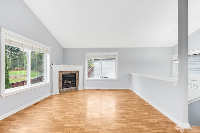 unfurnished living room featuring lofted ceiling, a fireplace, and light wood-type flooring