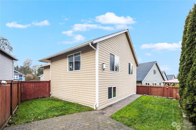 view of side of property featuring a patio area and a lawn