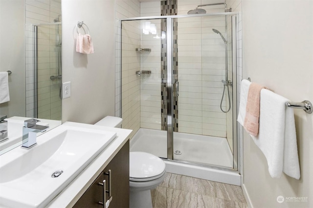 bathroom with walk in shower, vanity, and toilet