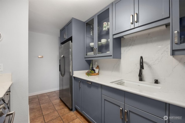 kitchen featuring sink, light tile patterned floors, backsplash, and stainless steel fridge with ice dispenser