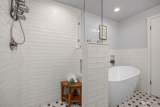 bathroom with tile patterned flooring, tile walls, and separate shower and tub