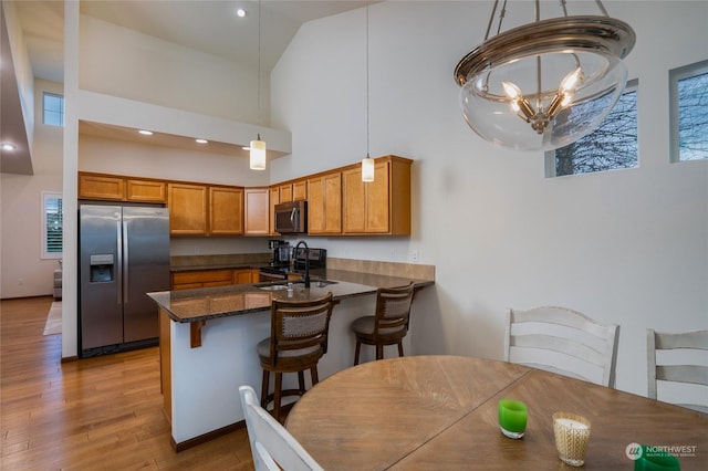 kitchen with decorative light fixtures, sink, a chandelier, kitchen peninsula, and stainless steel appliances