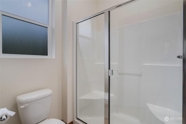 bathroom featuring toilet and a shower with shower door