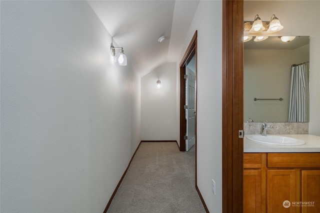 corridor with sink, vaulted ceiling, and light colored carpet