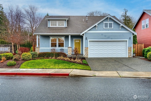 craftsman-style house featuring a garage, covered porch, and a front yard