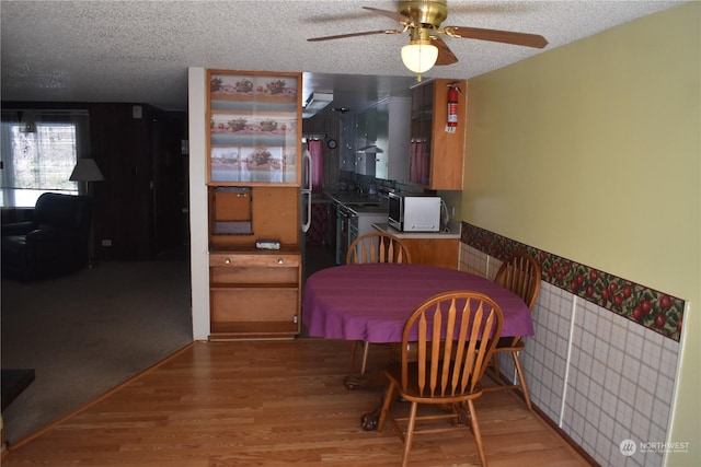 dining space featuring wood-type flooring, ceiling fan, and a textured ceiling