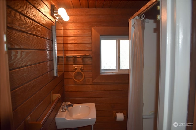 bathroom featuring sink, wooden ceiling, and wood walls