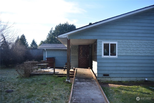 entrance to property with a wooden deck and a yard