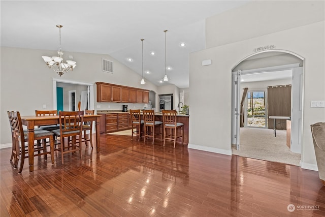 dining area featuring dark wood-type flooring, a chandelier, and high vaulted ceiling