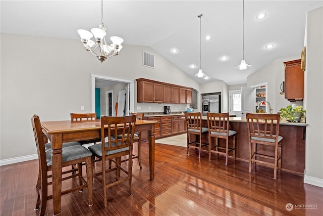 dining space with high vaulted ceiling, dark hardwood / wood-style floors, sink, and a chandelier