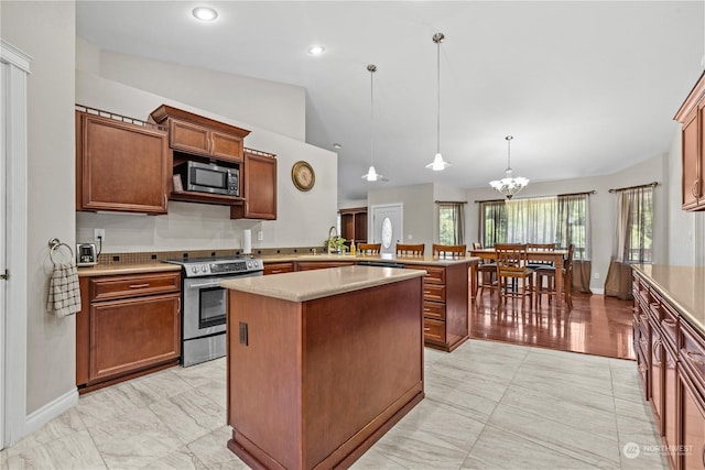 kitchen featuring vaulted ceiling, appliances with stainless steel finishes, sink, hanging light fixtures, and a center island