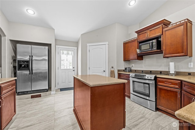 kitchen featuring stainless steel appliances, vaulted ceiling, and a kitchen island