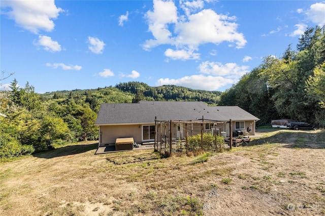 back of house featuring a jacuzzi and a lawn