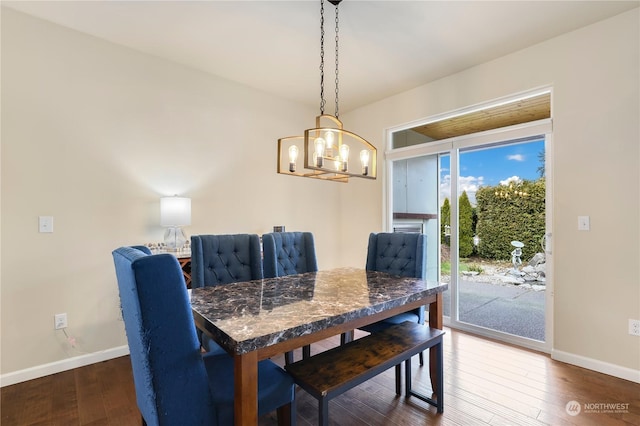 dining space with dark wood-type flooring and a notable chandelier