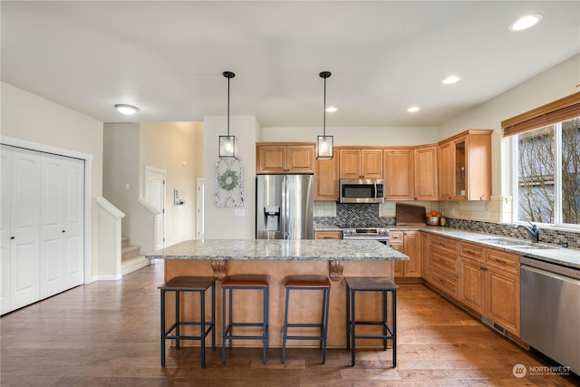 kitchen featuring hanging light fixtures, light stone countertops, a center island, and appliances with stainless steel finishes