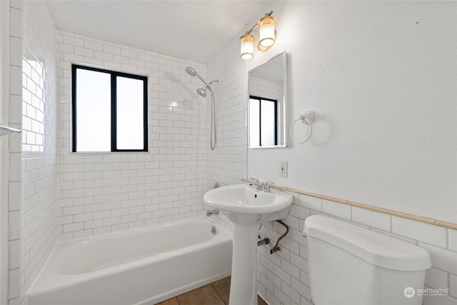 bathroom featuring tile patterned floors, toilet, tiled shower / bath combo, and tile walls