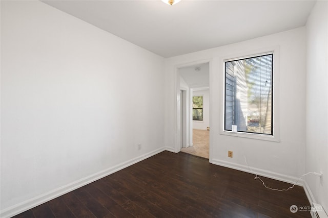 unfurnished room with dark hardwood / wood-style floors and baseboard heating