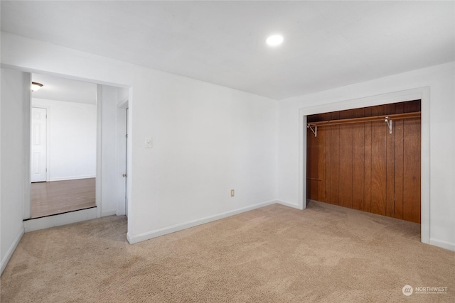 unfurnished bedroom with light colored carpet and a closet