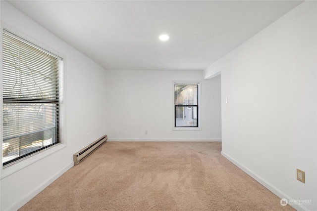 carpeted empty room featuring plenty of natural light and baseboard heating